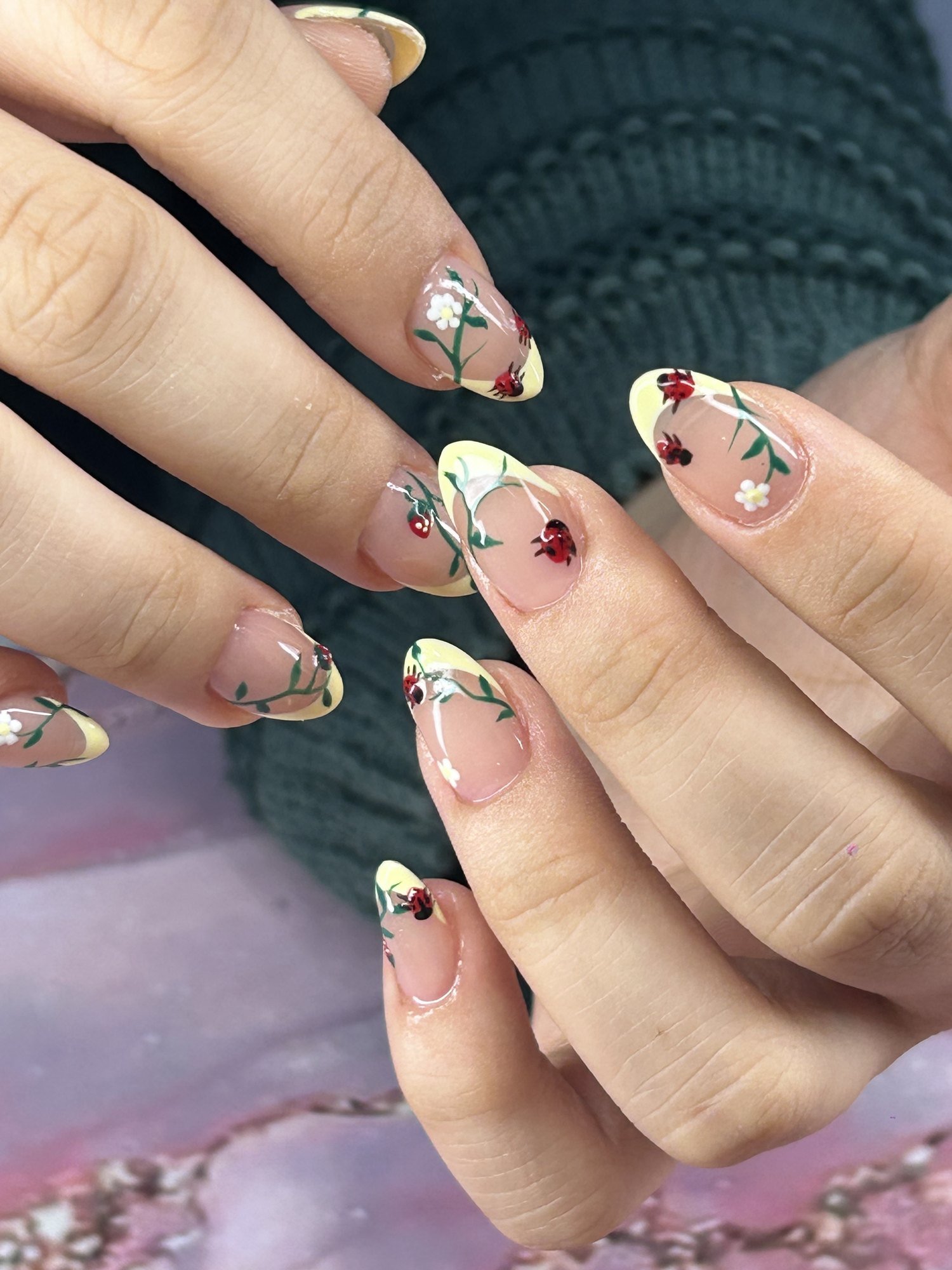 Gel-X extensions with yellow French tips and hand-painted ladybugs at Nailbox Co.