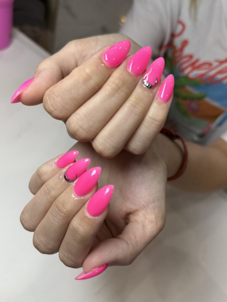 Hot pink stiletto nails with a chrome accent at Nailbox Co.