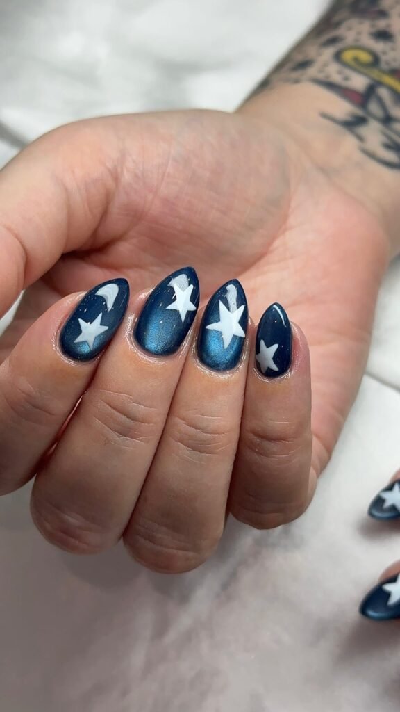 Navy cat-eye nails with hand-painted white stars at Nailbox Co.