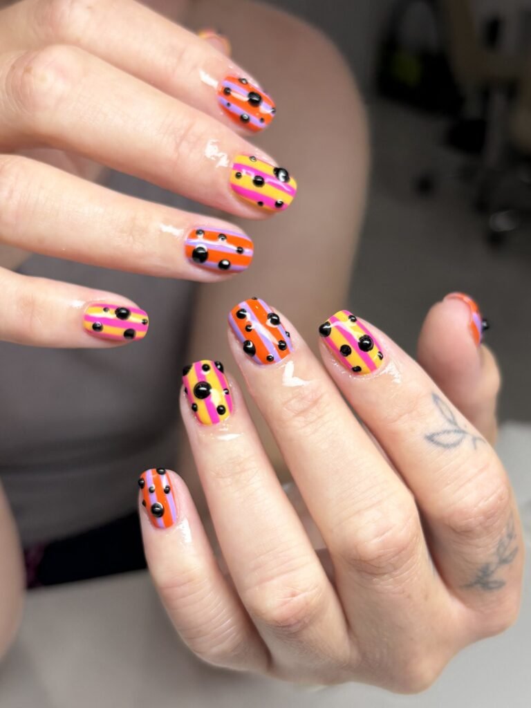 Orange and pink striped nails with 3D polka dots at Nailbox Co.